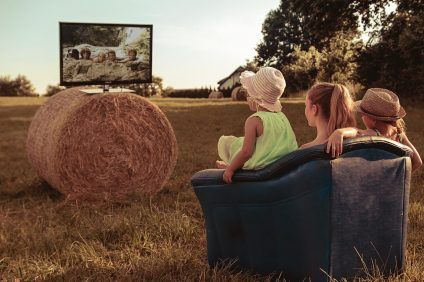 Familie schaut TV auf einem Feld