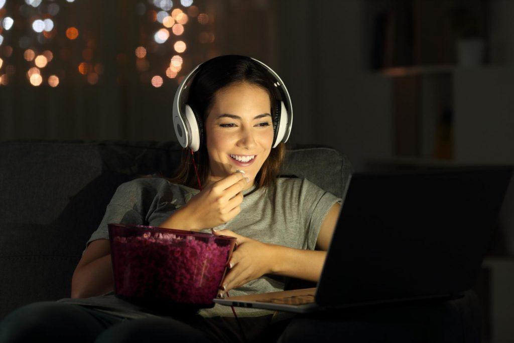 Frau mit Kopfhörer streamt Serie am Laptop
